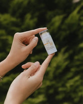 Person holding a small bottle with a green blurred background