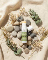 Lip balm on stones with dried flowers and leaves on a beige fabric background