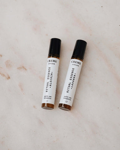 Two small bottles of 'Creme' on a light marble surface